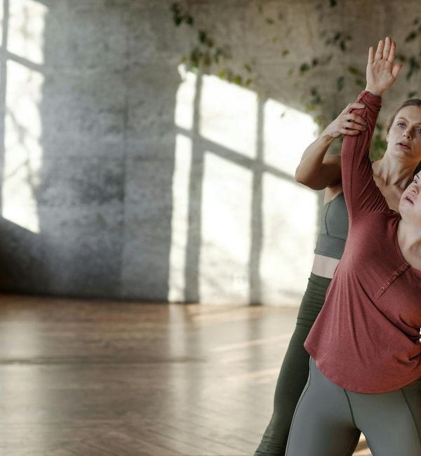 Person stretching on a yoga mat in a spacious, sunlit room.